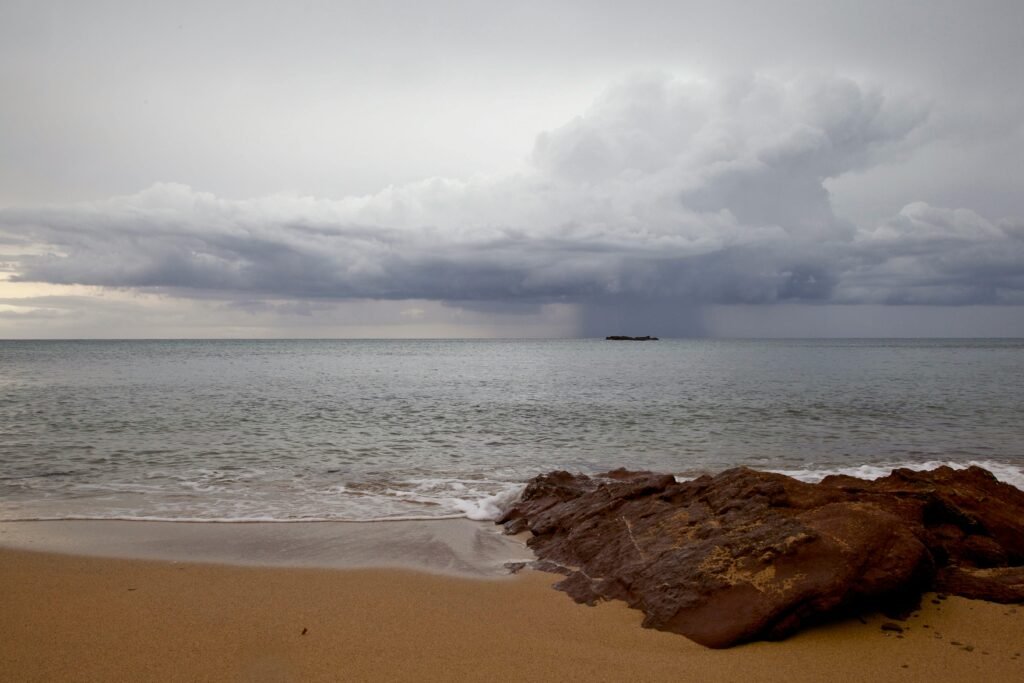 Dramatic storm clouds gather over Ciudadela de Menorca's sandy shoreline.