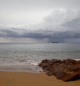 Dramatic storm clouds gather over Ciudadela de Menorca's sandy shoreline.